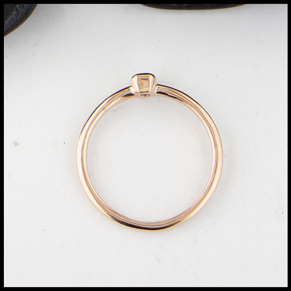 Profile view of simple 14K Rose Gold ring bezel set with a 0.09ct Emerald Cut Diamond.