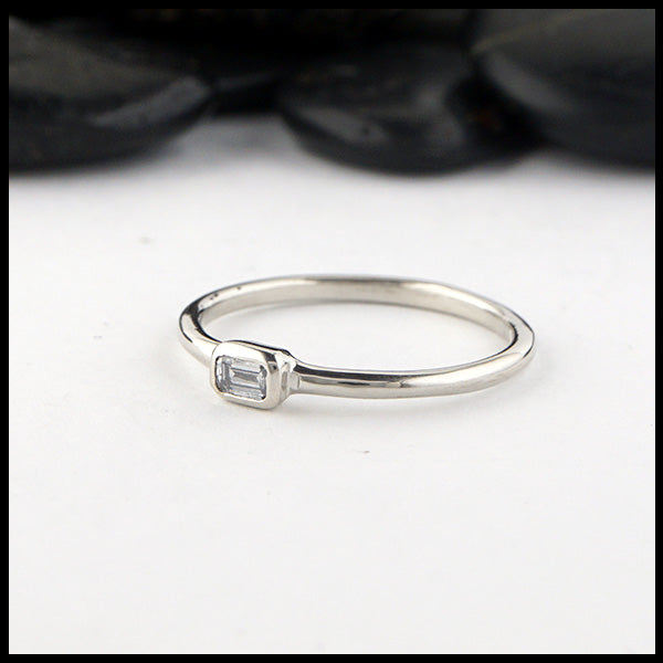 Simple 14K White Gold ring bezel set with a 0.09ct Emerald Cut Diamond.