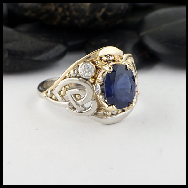 Custom ring in 14K Yellow and White Gold. Set with a center 9x7 2.40ct blue sapphire, two 3mm and two 1.5mm diamond accents.