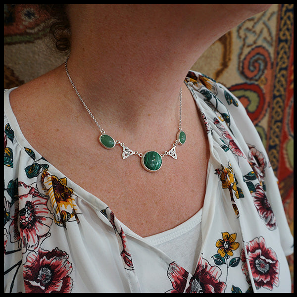 Celtic link necklace with a Malachite center stone and two side stones of Adventurine with two accent trinity knots. Shown being worn around the neck.