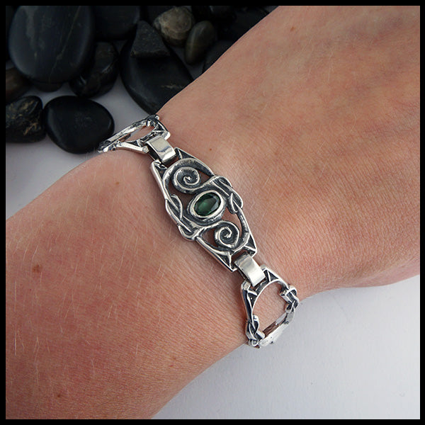 Celtic Spiral Link bracelet in Sterling Silver with Green Topaz. Made with three gemstone links & two open links, shown on a wrist.