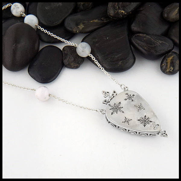 Reverse view of hand carved snowflakes on opal pendant