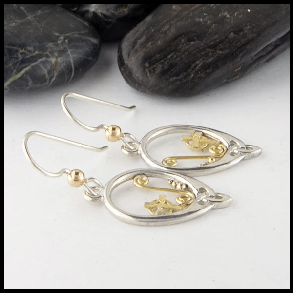 Profile view of custom cross drop earrings in silver and gold