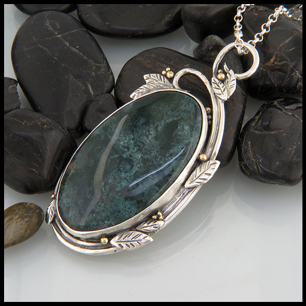 side view of the oval moss agate pendant showing the leaf and scroll details in silver and 18k yellow gold accent beads
