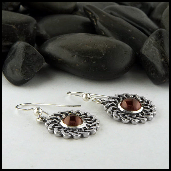 Profile view of celtic knot flower earrings with red garnet