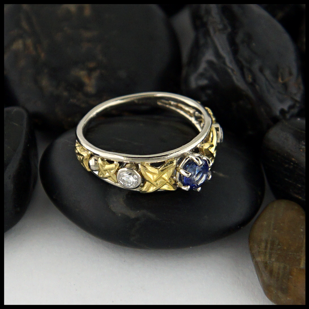 Custom Celtic ring with 14K White Gold frame and 18K Yellow Gold details. set with a Ceylon Sapphire and two 3mm Diamonds.